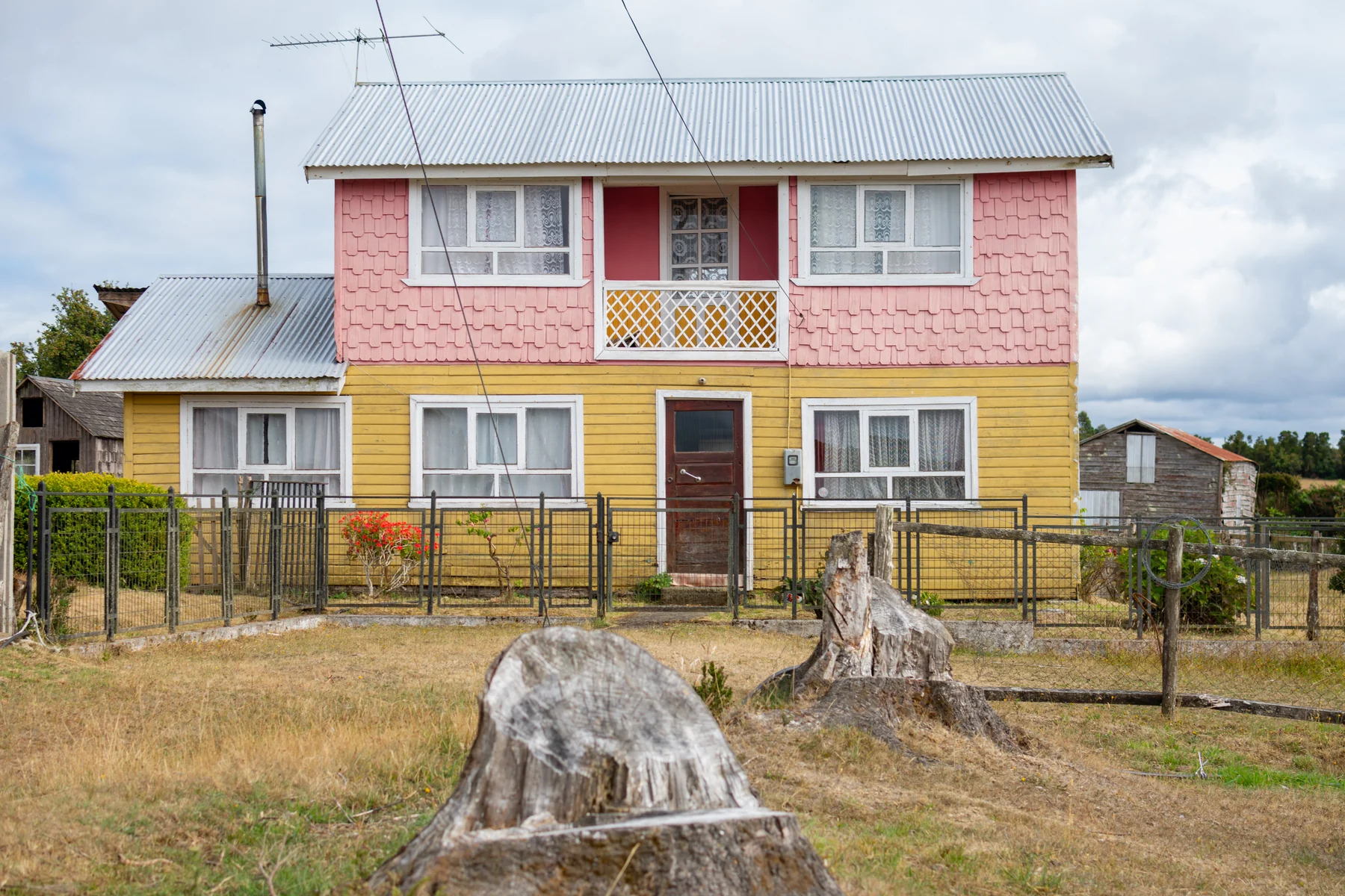Fachada de casa de dos pisos con revestimiento amarillo y rosado